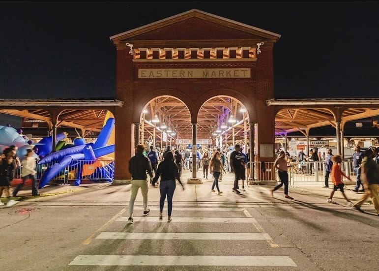 A shed at Eastern Market lit up with people mingling at Easter Market after Dark