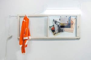 old glass window frame with an range track jacket and old photos